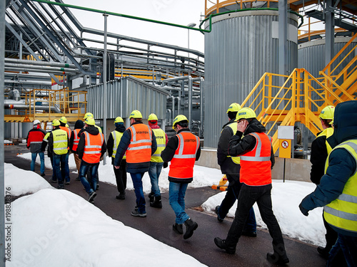 Factory inspection. group of visitors on the factory tour. people go in helmets and uniforms for an industrial enterprise. .auditors inspect production photo