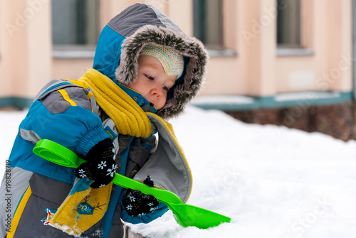 Little boy playing with snow and spade photo