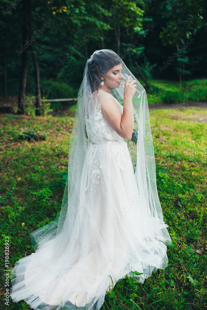 Bride with a glass of champagne under the veil