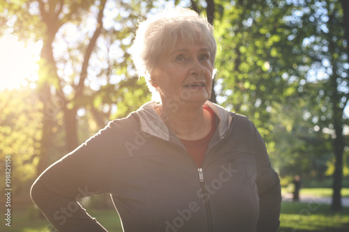 Fototapeta Naklejka Na Ścianę i Meble -  Smiling senior woman standing in park and enjoying in day.