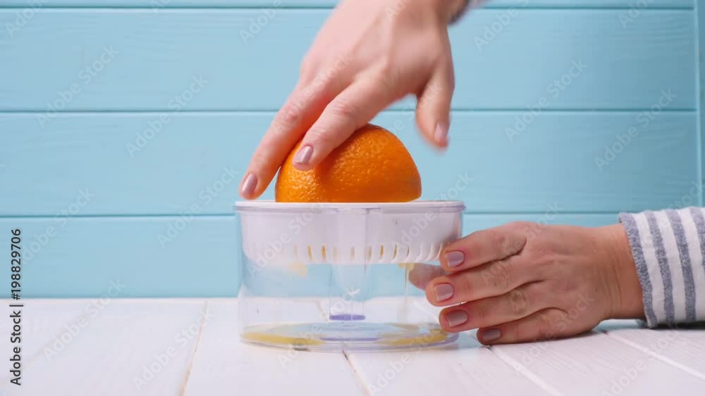girl makes orange juice through a juicer. close-up girl makes orange juice through a juicer. close-up