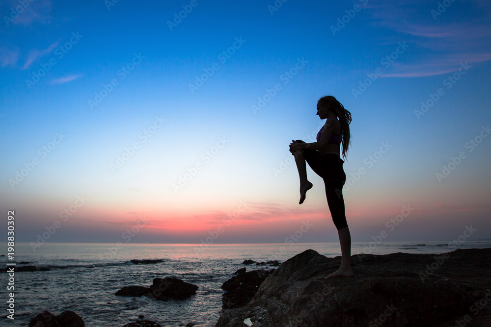 Yoga or Fitness woman silhouette on the sea during amazing sunset.  Healthy lifestyle.