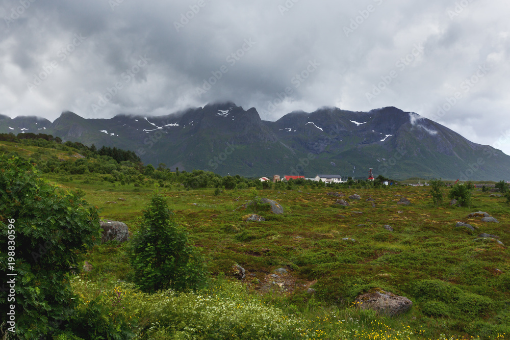 Typical scandinavian landscape with meadows, mountains and village. Lofoten islands, Norway.