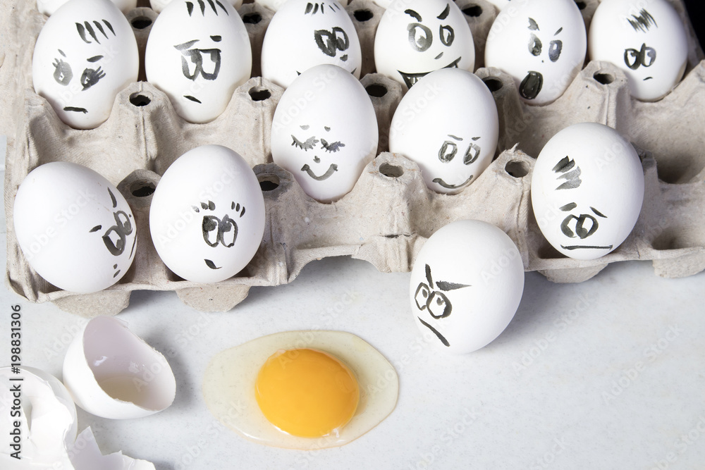 the Hen eggs in box. Eggs cover with drawings. Look like man face. Indignant eggs look at the broken egg. the Hen eggs in box. Eggs cover with drawings. Look like man face. Indignant eggs look at the broken egg.