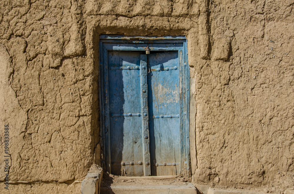 Old wooden door with ornaments in abandoned house in Oman