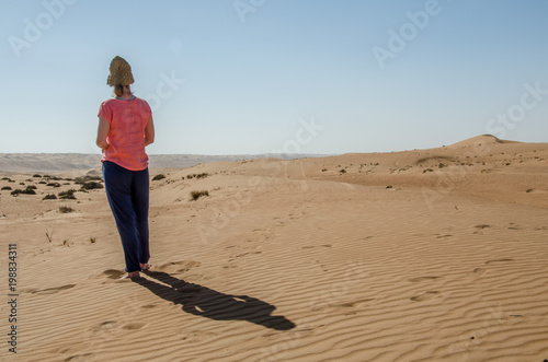 Girl standing alone in Wahiba sands desert looking at horizon © Mario