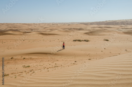 Girl walking alone through Wahiba sands deserts towards horizon
