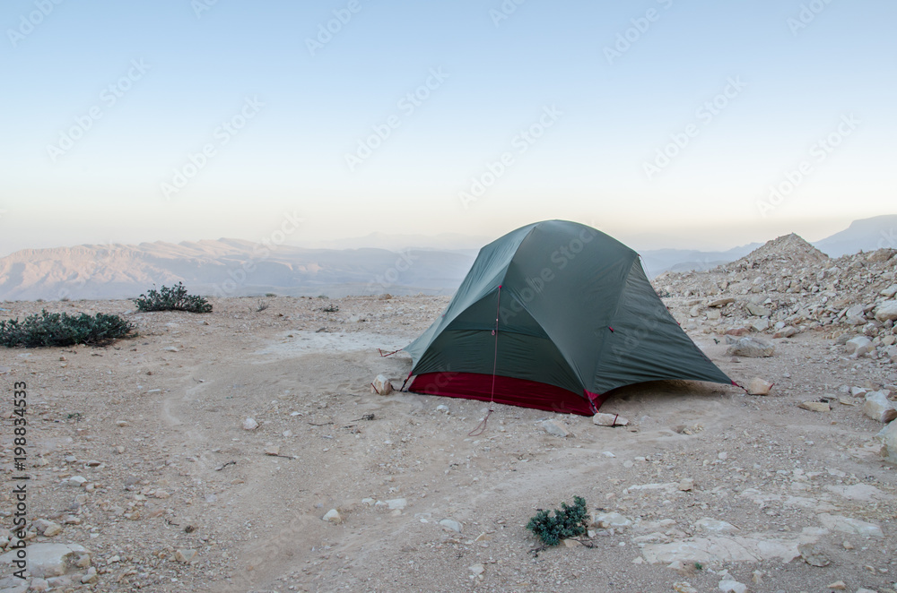 Wild camping in Oman with tiny tent on rocky underground in Oman mountains