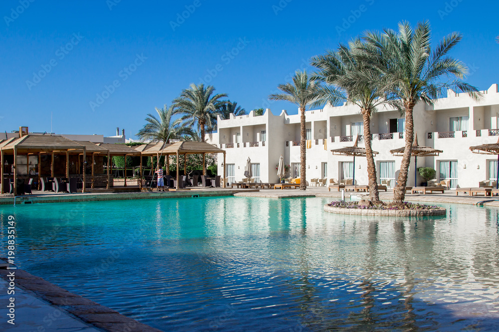 Hotel facade in sharm el sheikh with a deeep blue water in the swimming pool and palm trees, peaceful landscape
