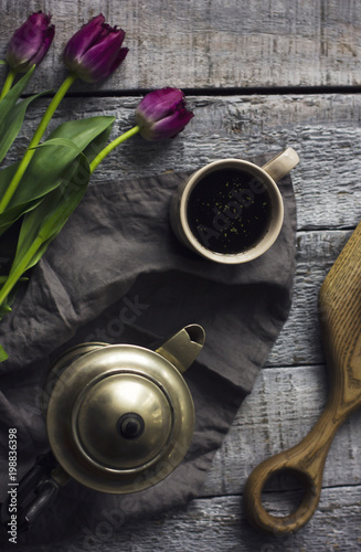 Still life with herbal tea, metal teapot and tulips on grey wooden background