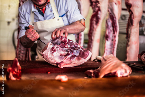 Quadro su tela butcher cut raw meat of a pig with a knife at table in the slaughterhouse