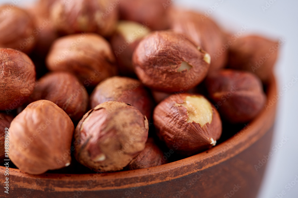 Hazelnuts in wooden bowl on wihite background with copy space, top view, selective focus. Hazelnuts in wooden bowl on wihite background with copy space, top view, selective focus.