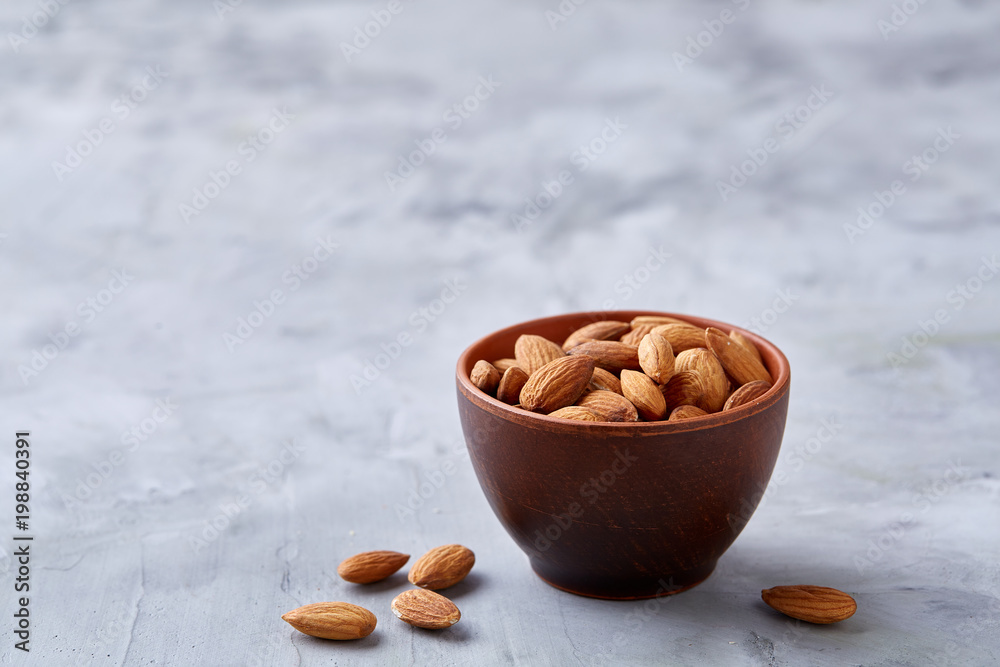 Bowl of almonds on white textured background, top view, close-up, selective focus. Bowl of almonds on white textured background, top view, close-up, selective focus.