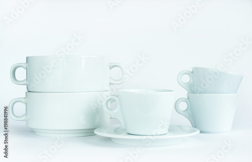 Minimalistic still life: set of simple elegant white tableware on white background. Soft light, high key.