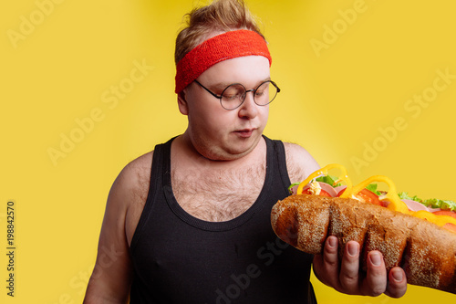 Joyful fat man is smelling sandwich and smiling photo