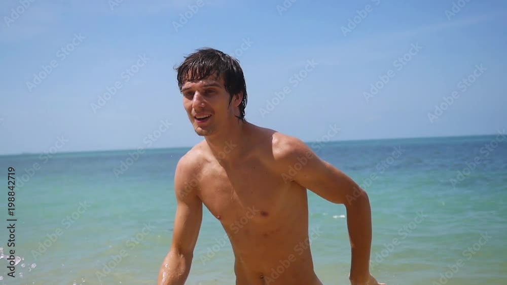Young handsome happy man running on the beach from the sea at sunny day in slow motion. 1920x1080 Young handsome happy man running on the beach from the sea at sunny day in slow motion. 1920x1080