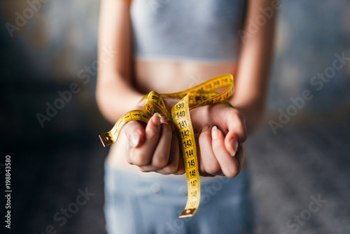 Tableau sur toile Skinny female hands are tied with measuring tape