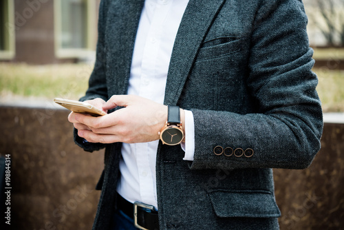 Confident man in gray jacket using smartphone, elegant business 