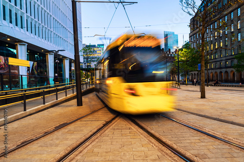 Light rail yellow tram in the city center of Manchester, UK in the evening