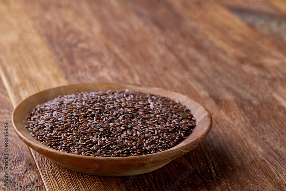 Flax seeds in a plate on wooden background, top view, close-up. Flax seeds in a plate on wooden background, top view, close-up.