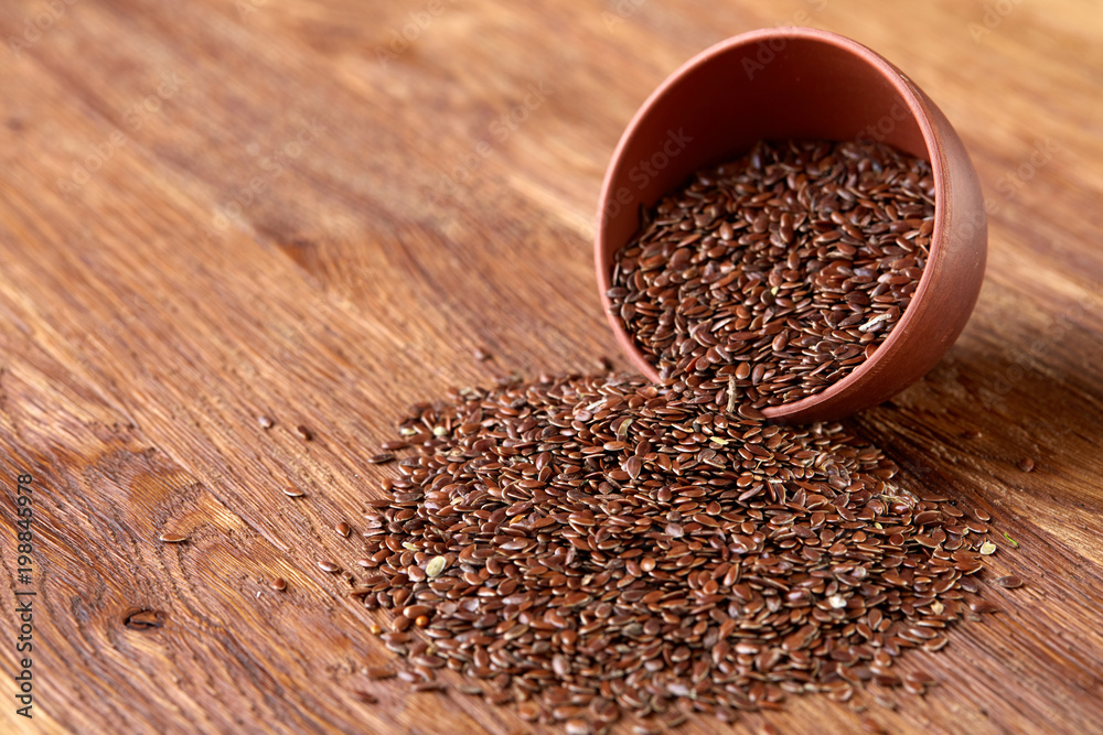 An overturned ceramic bowl with linseeds on a rustic background, close-up, shallow depth of field, selective focus An overturned ceramic bowl with linseeds on a rustic background, close-up, shallow depth of field, selective focus