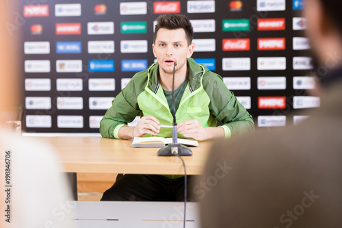 Obraz na płótnie Waist-up portrait of handsome young soccer player looking at journalists and ans