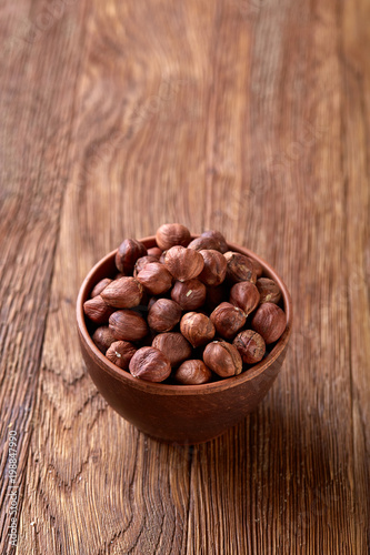 Hazelnuts in wooden bowl on wihite background with copy space, top view, selective focus.