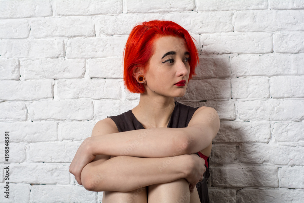 Teenage girl sitting at the white brick wall. She gripped her knees with her hands.
Teenage girl sitting at the white brick wall. She gripped her knees with her hands.