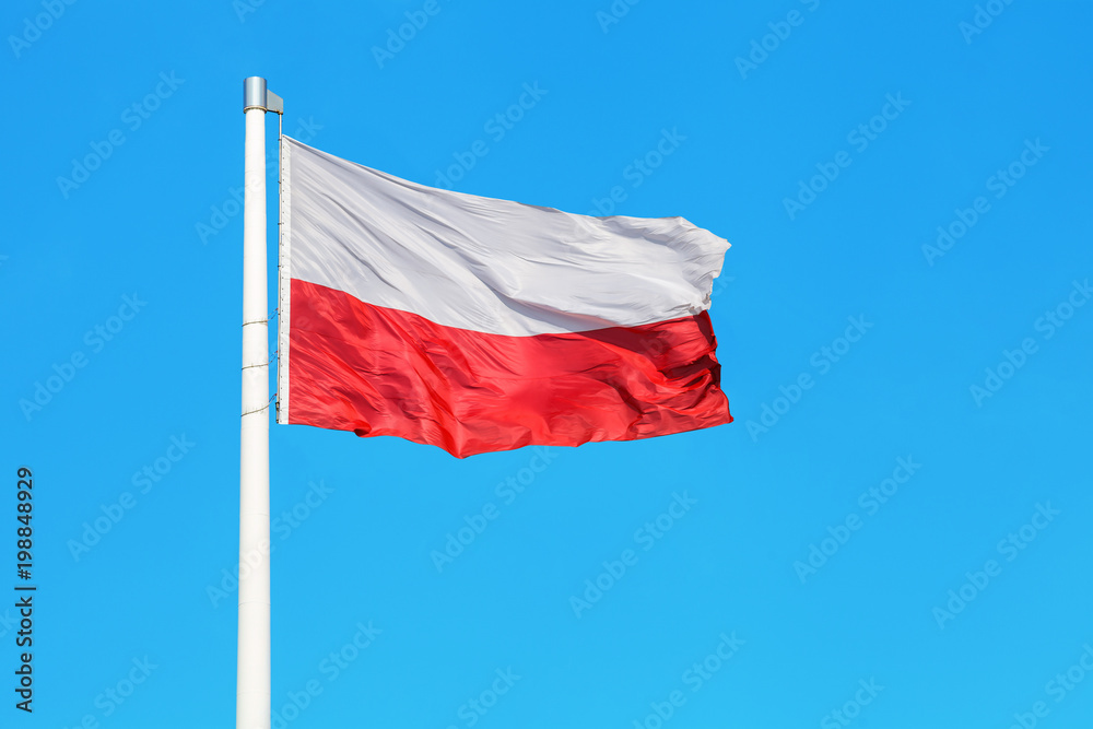 Polska flaga narodowa powiewająca na tle niebieskiego nieba Polska flaga narodowa powiewająca na tle niebieskiego nieba