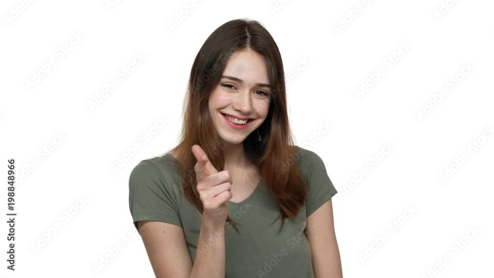 Portrait of attractive woman 20s in casual t-shirt gesturing finger on camera meaning hey you, over white background. Concept of emotions Portrait of attractive woman 20s in casual t-shirt gesturing finger on camera meaning hey you, over white background. Concept of emotions