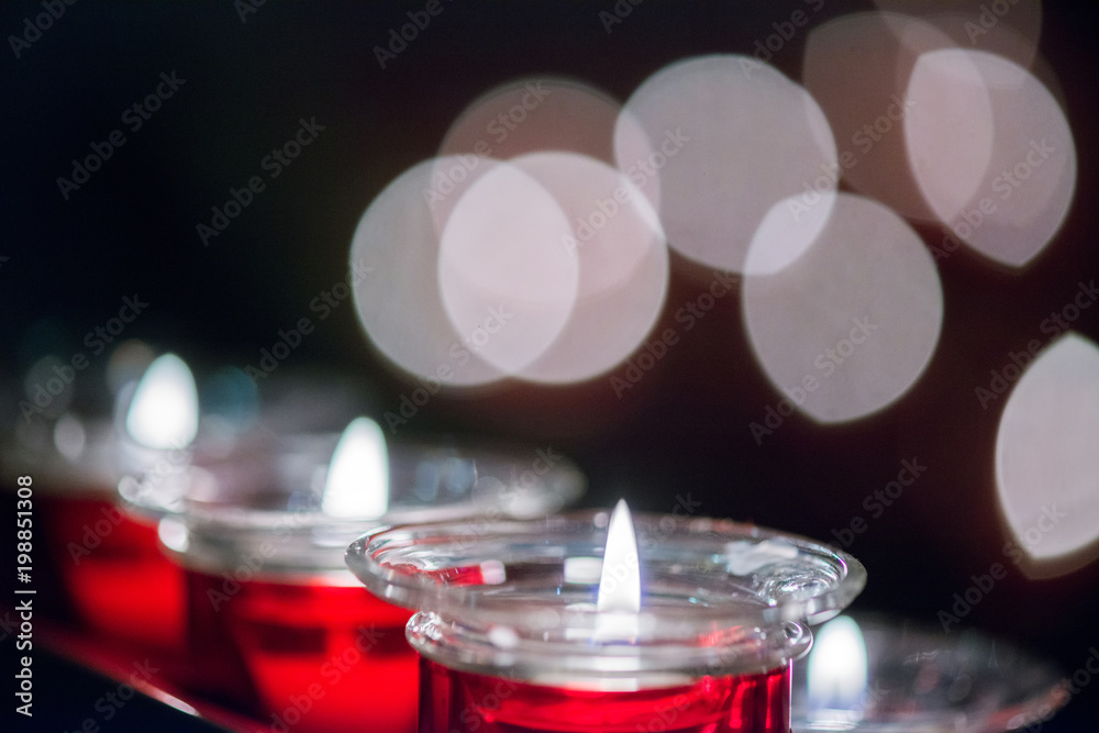 Many Red Wax Candle in Glass with beautiful bokeh on the background. Close-up.
