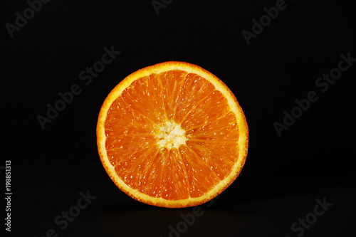 Orange, a whole orange, half orange, isolated on a black background. Front view. Copy space. Healthy nutrition, the concept of nutrition. A sweet ripe orange.