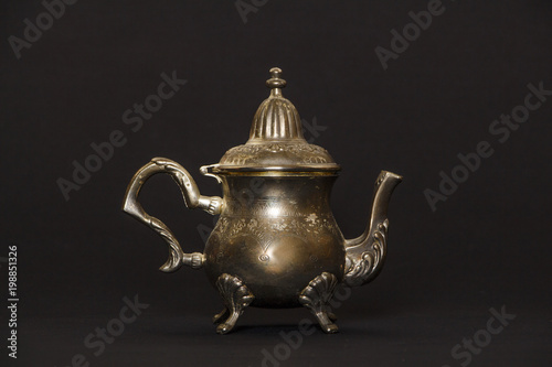 Silver antique teapot on a black background. A beautiful antique silver teapot. The kettle is silver.

