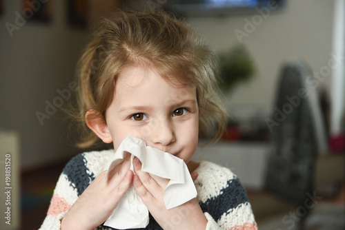 Sick little girl covering her nose with handkerchief