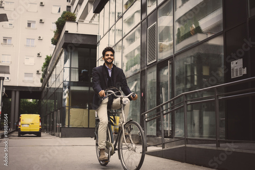 Smiley businessman driving bike on street. © Mladen