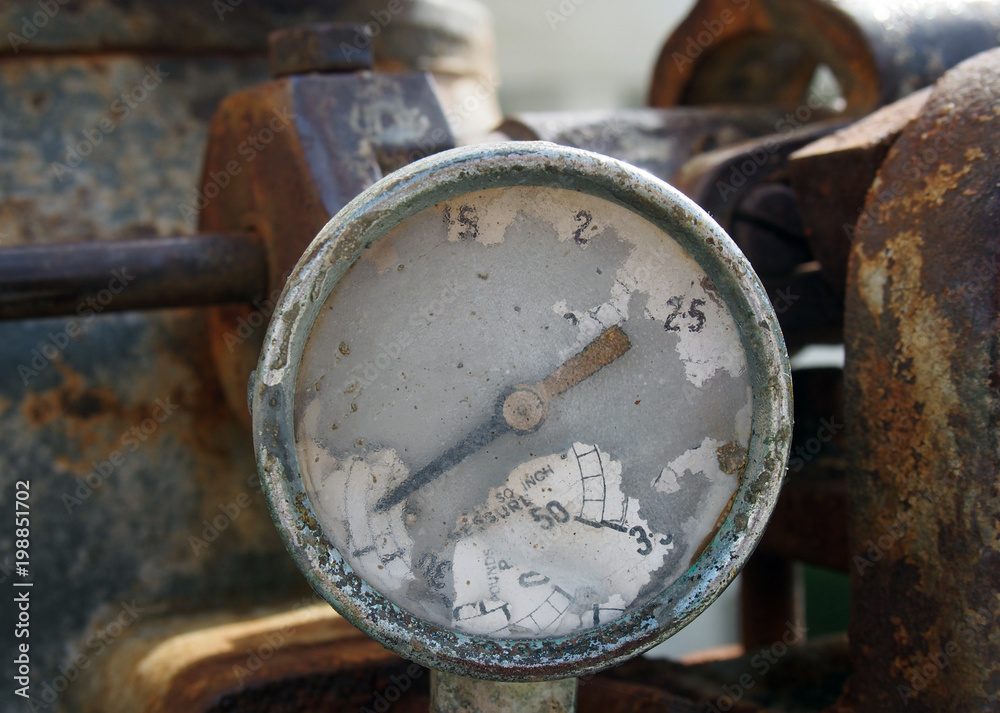 Old broken gauge with traces of numbers on the dial on a large old rusty engine Old broken gauge with traces of numbers on the dial on a large old rusty engine