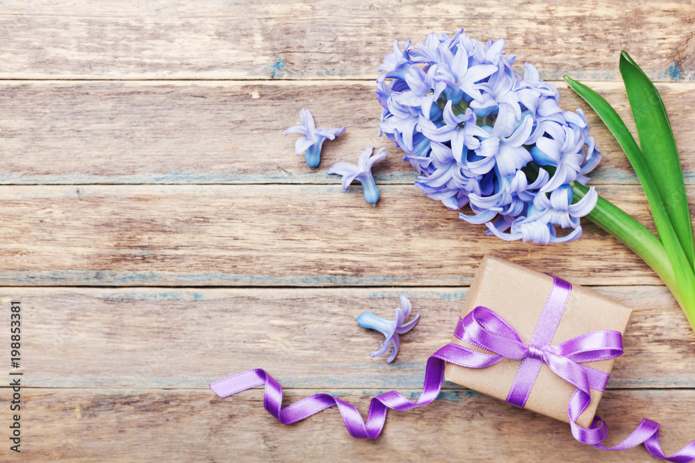 Happy Mothers Day holiday greeting card with hyacinth flowers and gift or present box on wooden rustic table. Top view.