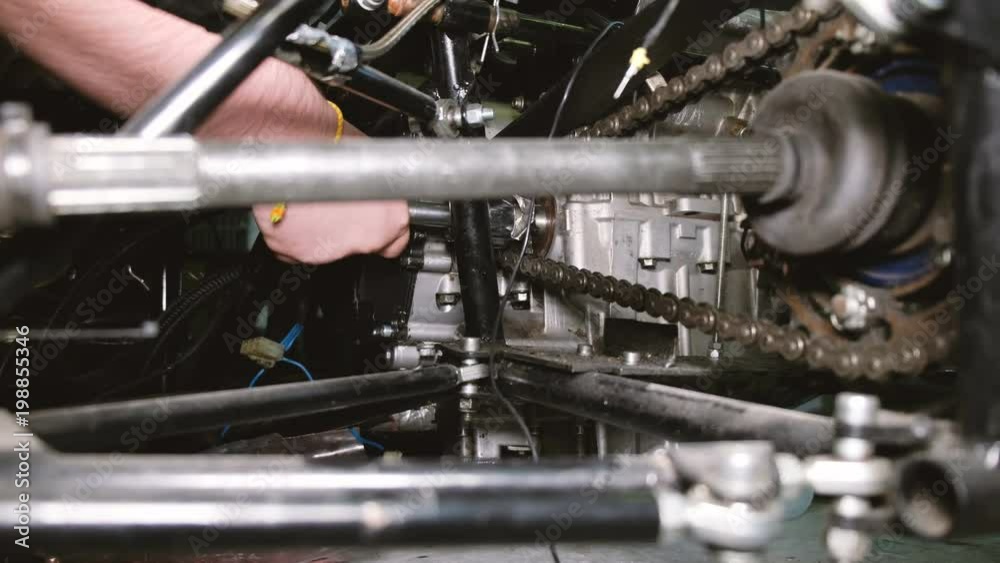 The team of car mechanics removes the internal combustion engine from the race car. The team of car mechanics removes the internal combustion engine from the race car.