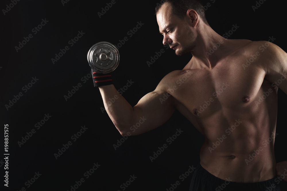 Strong athletic man with dumbbell showes naked muscular body Strong athletic man with dumbbell showes naked muscular body