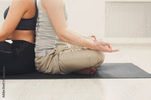 Young couple meditating together, back to back