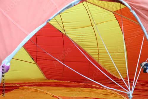 Bright orange and yellow hot air balloon opening on the ground 