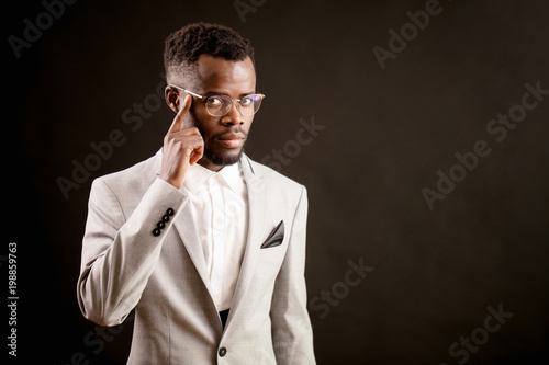 serious handsome businessman with black skin in glasses is touching his temple. grey thoughts.