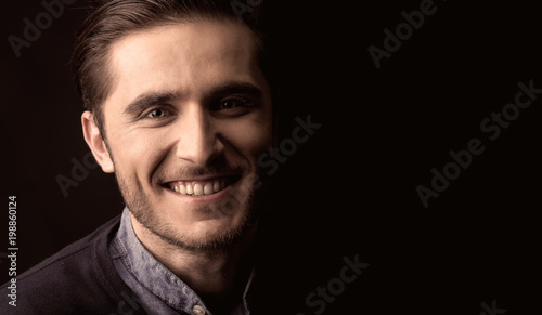 young man close up portrait, on black background