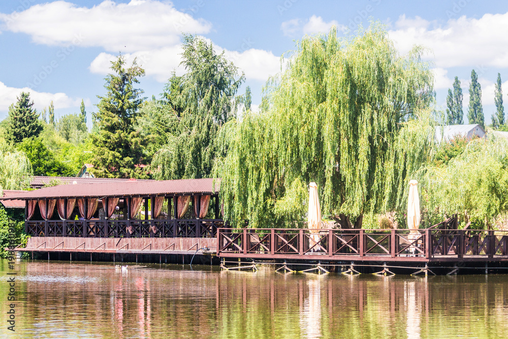 Naklejka premium Cafe bar and furniture by the lake in summer day