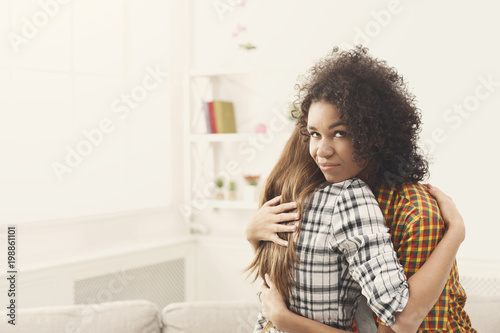 Fotografie Woman with sly facial expression embracing lfriend