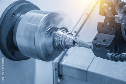 The CNC lathe machine drilling the metal cone shape part in the light blue scene.