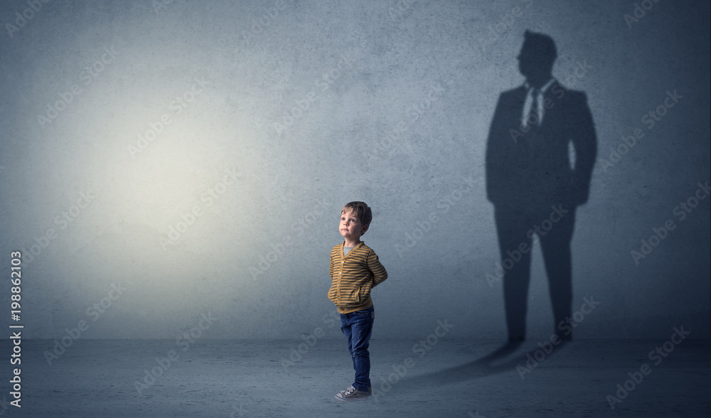 Obraz premium Little boy imagine that he will be businessman and illustrating his future in a big shadow 