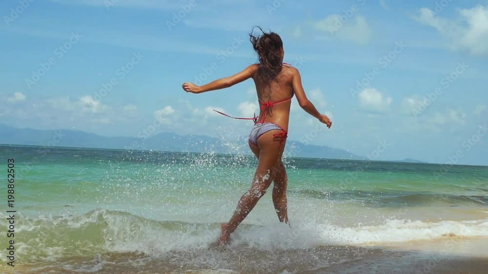 Joyful young slim woman in bikini running along the exotic white sandy beach through the seaand splashing water on sunny summer day. slow motion. 1920x1080 Joyful young slim woman in bikini running along the exotic white sandy beach through the seaand splashing water on sunny summer day. slow motion. 1920x1080