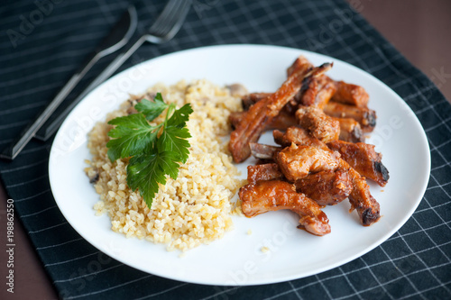 grilled pork with rib in white dish, served with bulgur
