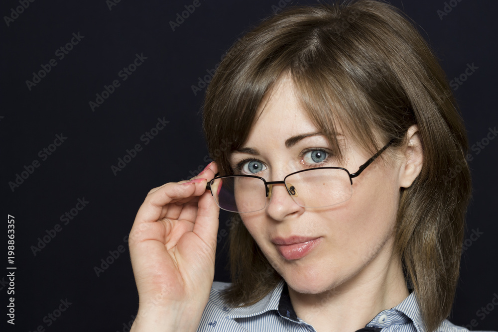 Portrait of a beautiful girl who looks over her glasses. Business woman. Copy space. Portrait of a beautiful girl who looks over her glasses. Business woman. Copy space.